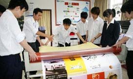 教师正在指导学生实际操作冷裱机